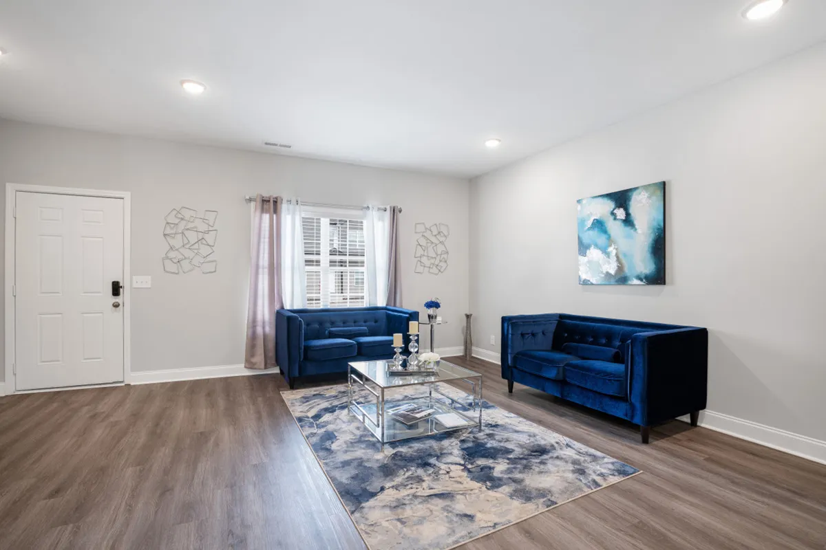 A contemporary living area with two blue sofas, a glass coffee table, and decorative wall art, arranged to foster group conversation, relaxation, and entertainment after exploring the local area.