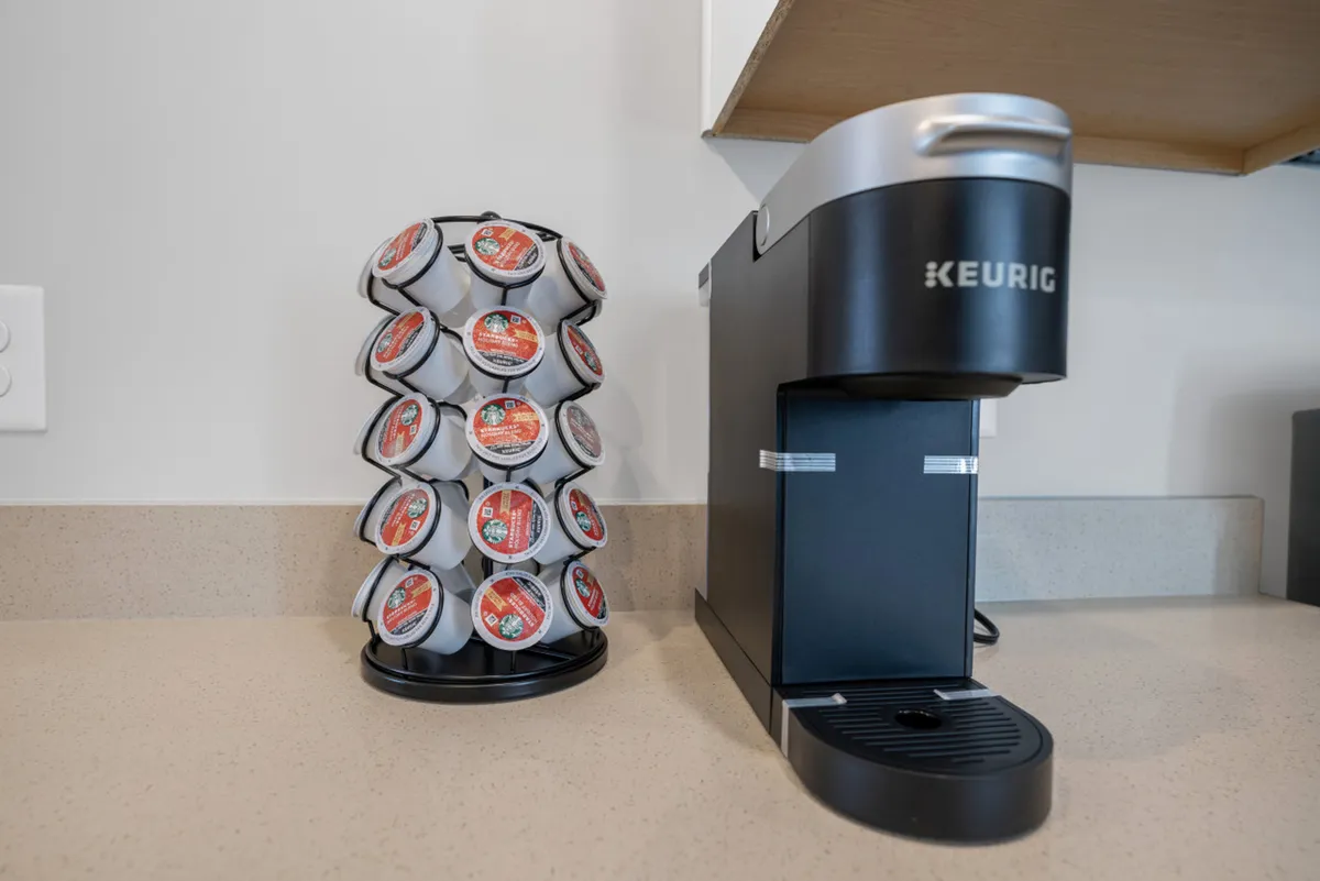 A close-up of a Keurig coffee maker and K-Cup holder in a cozy kitchen nook, ready for use. The scene suggests a welcoming morning routine, with the convenience of brewing coffee at home before starting a productive day.