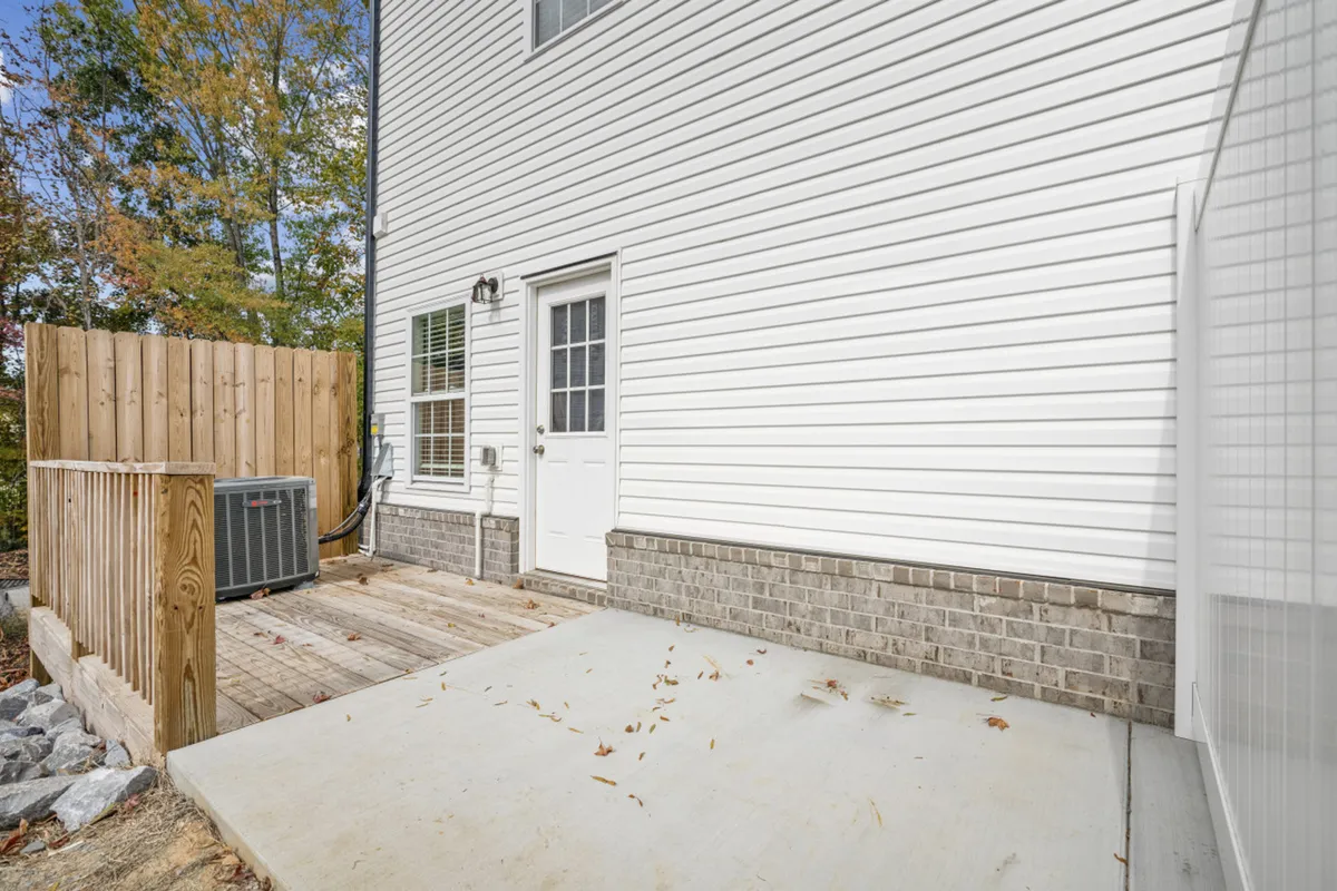 A bright exterior shot of a spacious wooden deck attached to the home, bordered by a white wall and a fenced area. The deck is ideal for outdoor meals, barbecues, and relaxed family evenings, with easy access to the outdoors after days spent exploring local attractions.