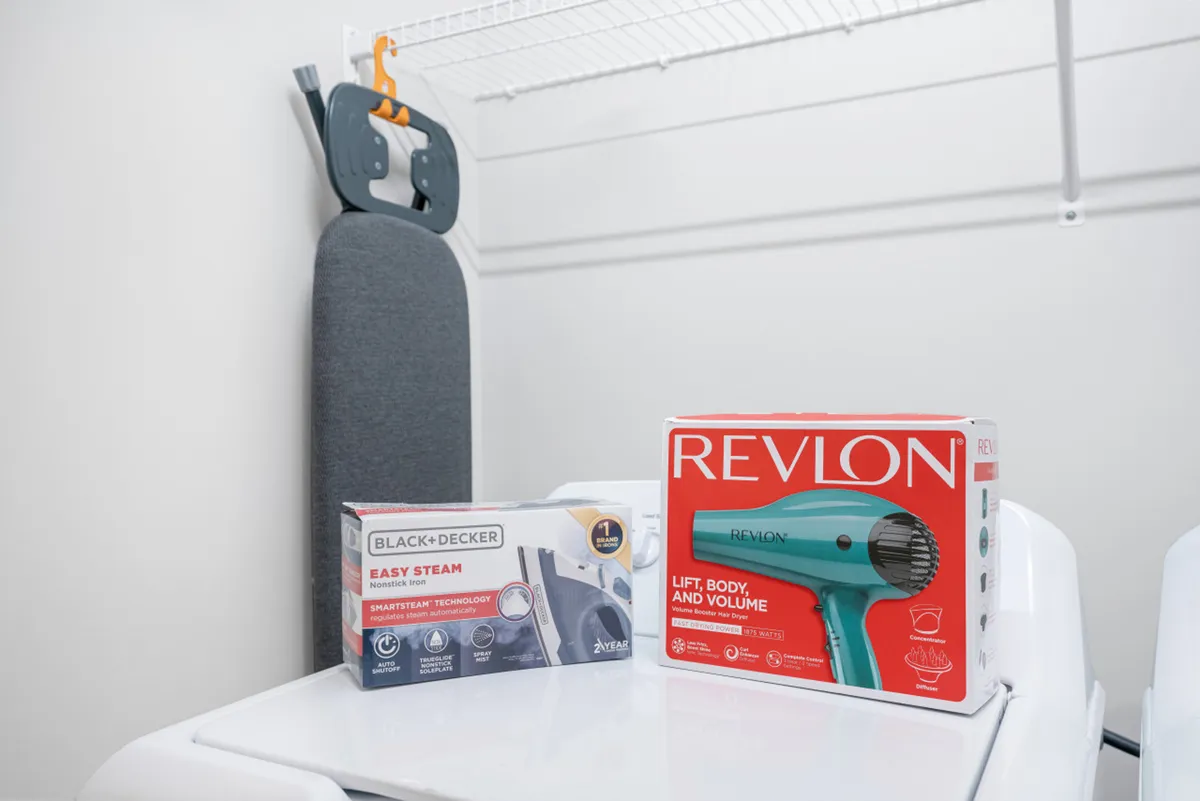 A practical scene showing an iron and ironing board alongside a hair dryer, set up within a tidy interior space. The area projects functionality and attention to guests' everyday needs.